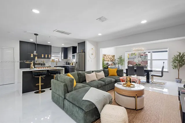 a living room with furniture kitchen view and a large window