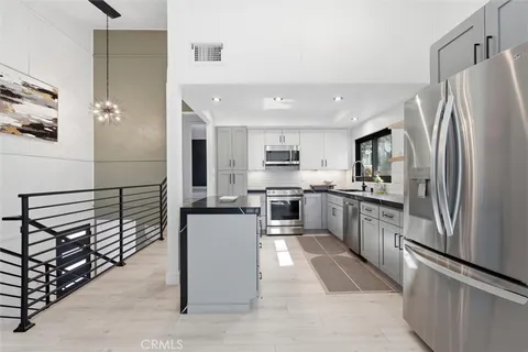 a kitchen with granite countertop a refrigerator a sink and white cabinets