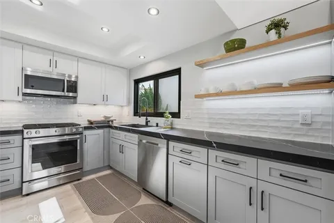 a kitchen with granite countertop a sink and stainless steel appliances