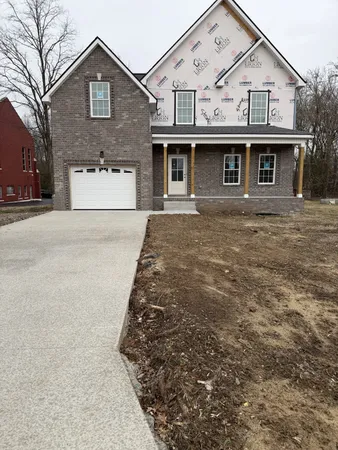 a view of a big house with a large tree and wooden fence