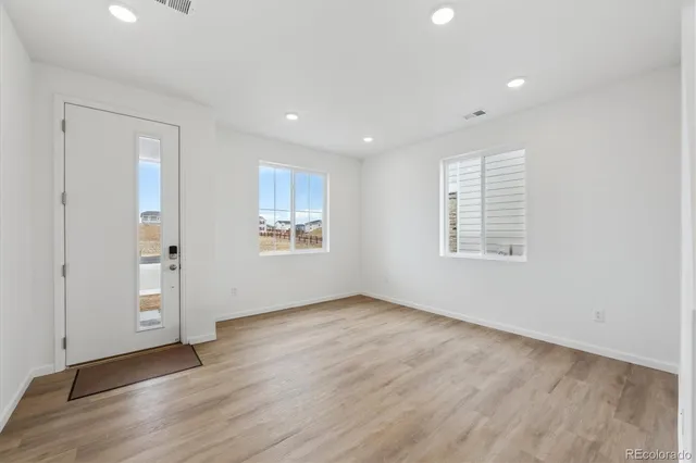 an empty room with wooden floor and windows