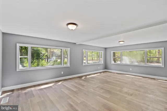 a view of an empty room with wooden floor and windows