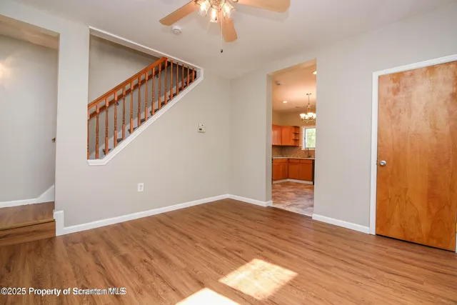a view of an empty room with wooden floor and a chandelier