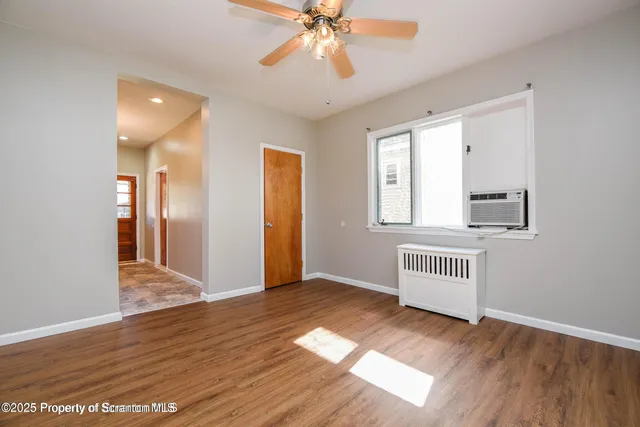 a view of an empty room with wooden floor and a window