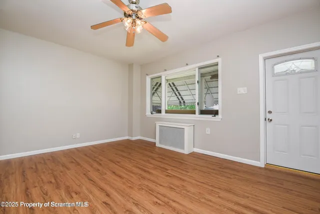 a view of empty room with wooden floor and fan