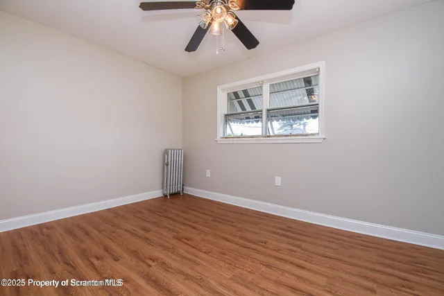 a view of an empty room with wooden floor and window