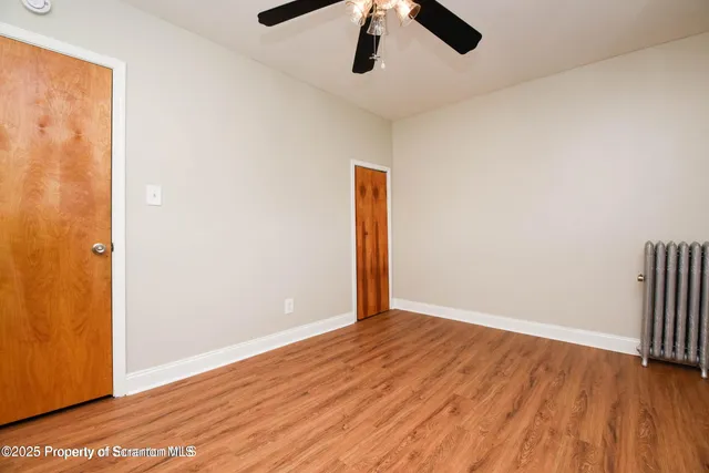an empty room with wooden floor cabinet and windows