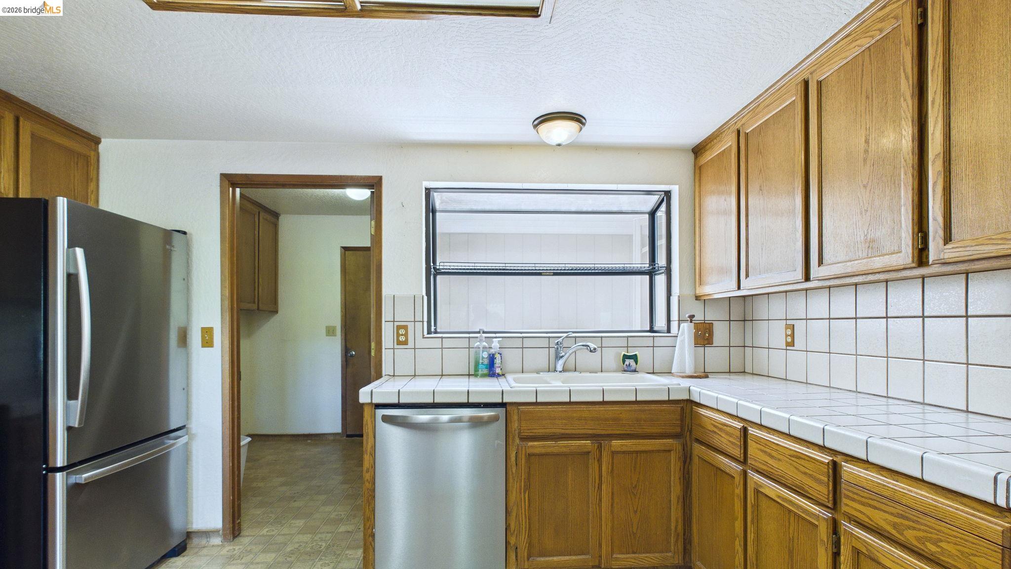 23686 Marble Quarry Road, Unit 72 Columbia, CA 95310 - Photo 7 of 35 Kitchen featuring wood cabinetry, a stainless steel refrigerator, and a stainless steel dishwasher