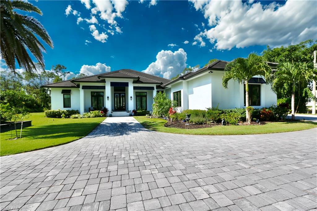 6688 Hunters Road Naples, FL 34109 - Photo 1 of 43 a front view of a house with a yard and potted plants