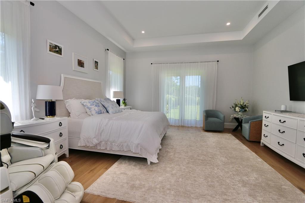 6688 Hunters Road Naples, FL 34109 - Photo 15 of 43 a bedroom with a bed and a flat tv screen on dresser