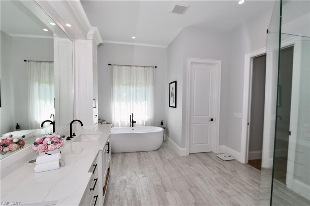 6688 Hunters Road Naples, FL 34109 - Photo 16 of 43 a bathroom with a bathtub sink and mirror