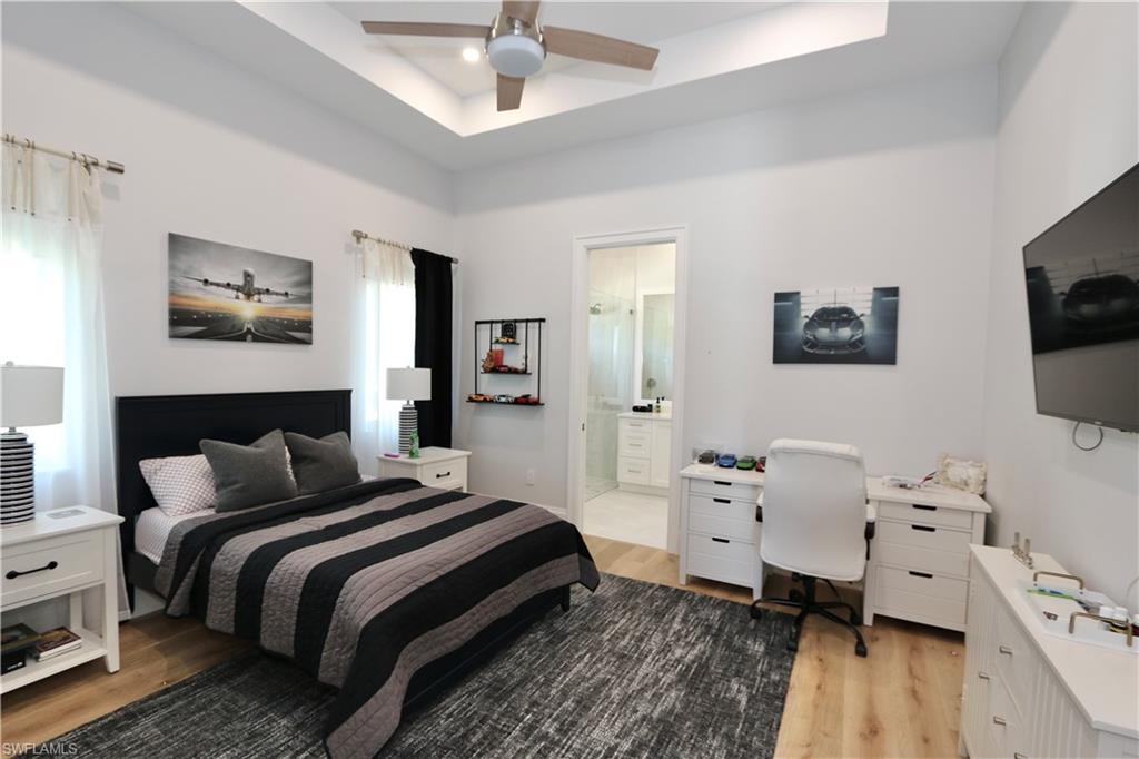 6688 Hunters Road Naples, FL 34109 - Photo 22 of 43 a bedroom with a bed and a flat tv screen on dresser