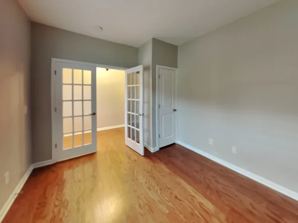 an empty room with wooden floor and windows