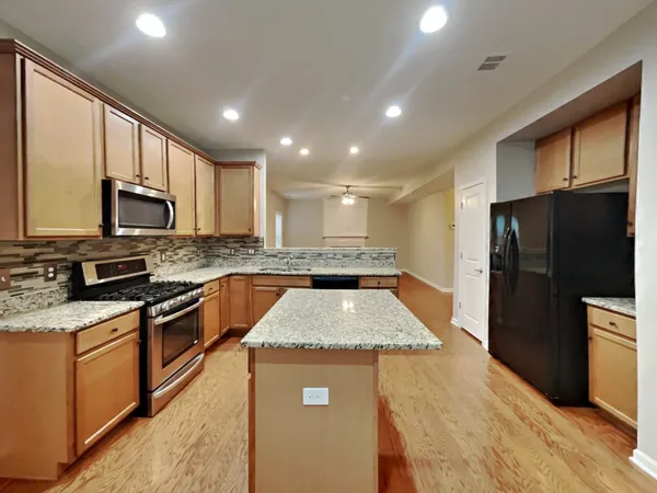 a kitchen with stainless steel appliances granite countertop a refrigerator a stove top oven a sink and dishwasher