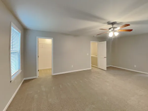 an empty room with windows and fan