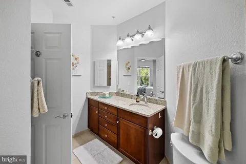 a bathroom with a granite countertop sink a toilet and mirror