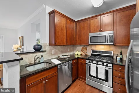 a kitchen with stainless steel appliances granite countertop a stove a sink and a microwave