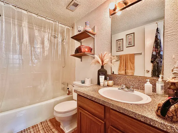 a bathroom with a granite countertop sink toilet and a mirror