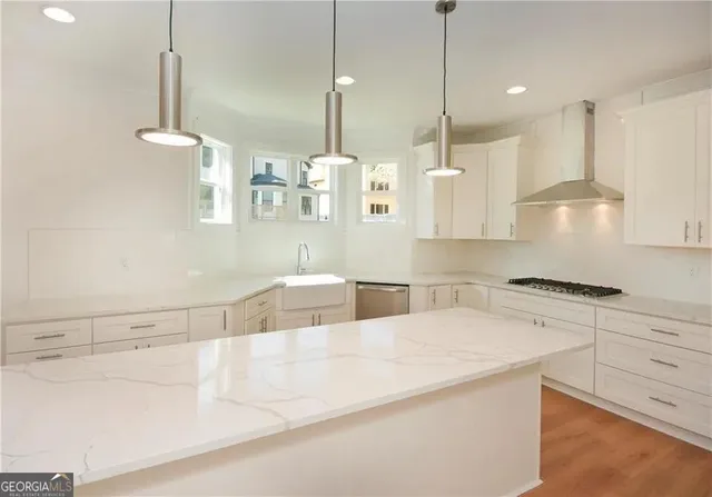 a large kitchen with a large counter top a sink stainless steel appliances and cabinets