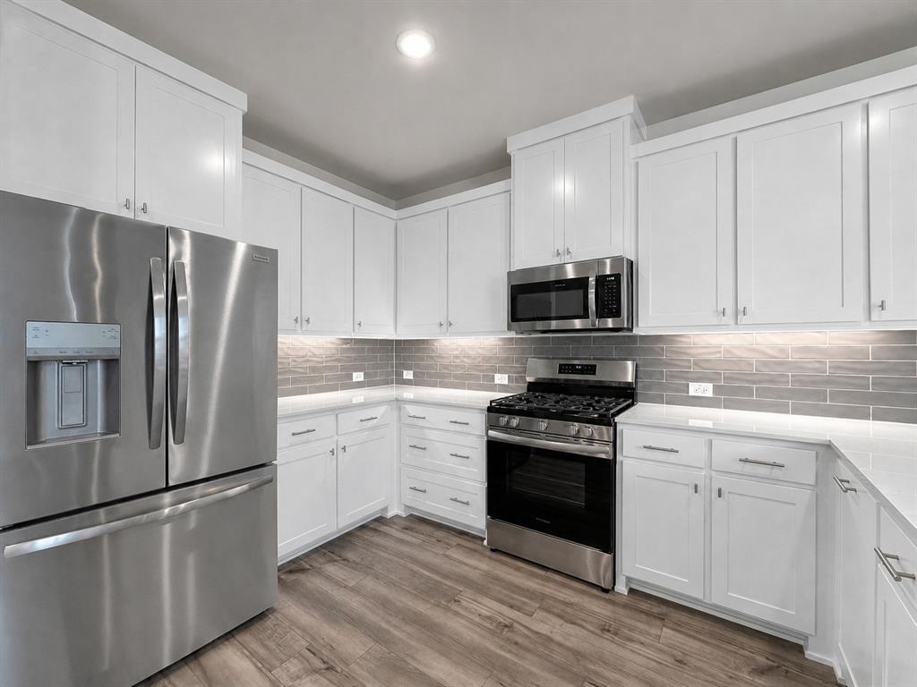 8876 Samara Street Frisco, TX 75035 - Photo 7 of 28 a kitchen with granite countertop white cabinets and stainless steel appliances