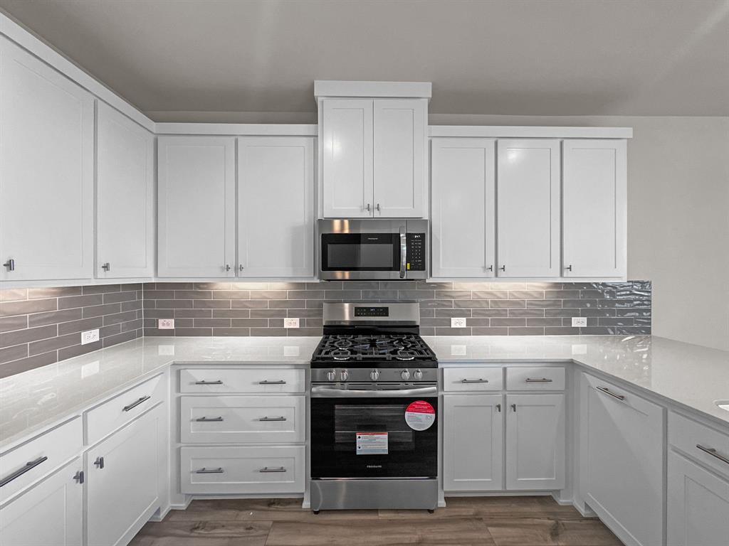 8876 Samara Street Frisco, TX 75035 - Photo 8 of 28 a kitchen with white cabinets and appliances