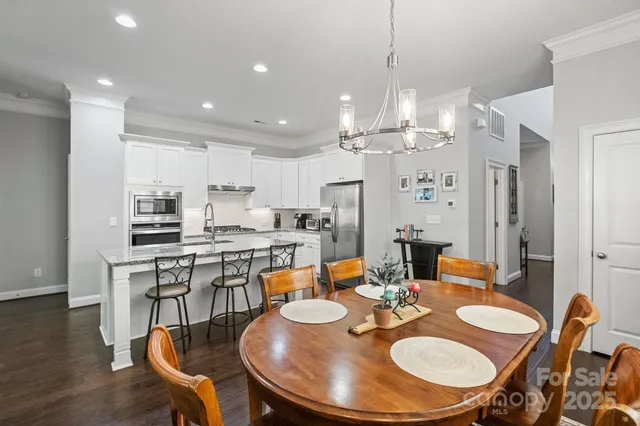 a kitchen with stainless steel appliances kitchen island granite countertop a table chairs sink and cabinets