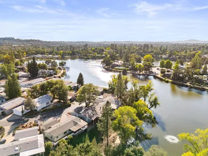 an aerial view of city and lake with trees all around