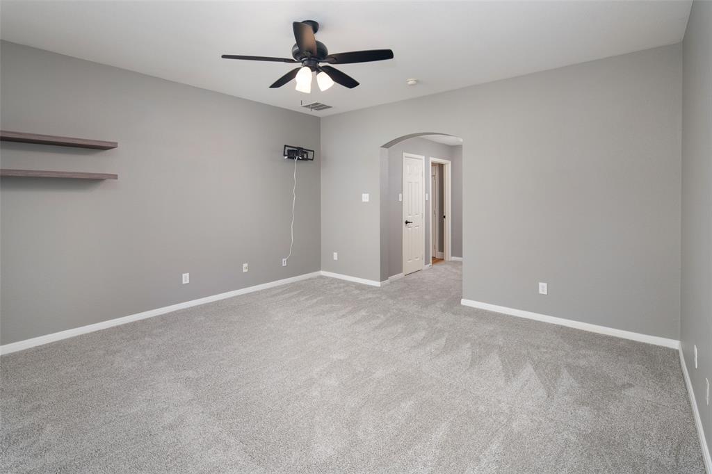 1019 Vaughan Lane Tioga, TX 76271 - Photo 23 of 40 Spacious room featuring gray wall paint, light-colored patterned carpeting, white baseboards, and a ceiling fan with integrated lighting