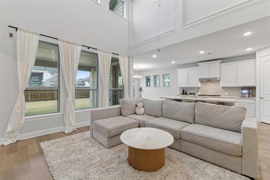 4150 Gambel Road Prosper, TX 75078 - Photo 11 of 39 Living area featuring light wood-style floors, a chandelier, and a high ceiling