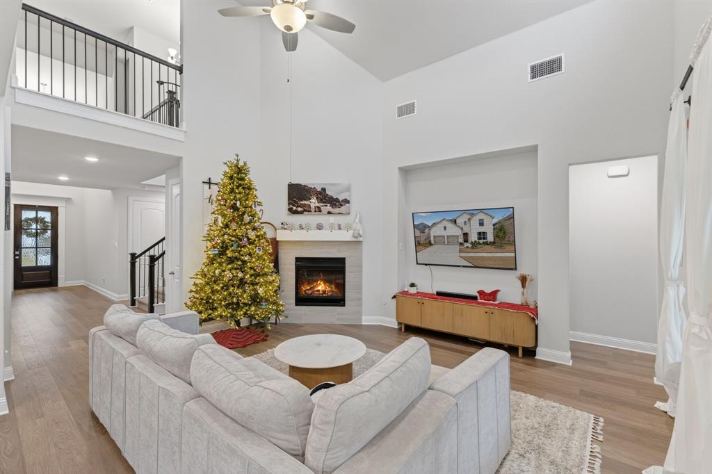 4150 Gambel Road Prosper, TX 75078 - Photo 12 of 39 Living room featuring high vaulted ceiling, a tiled fireplace, ceiling fan, light wood-type flooring, and stairs