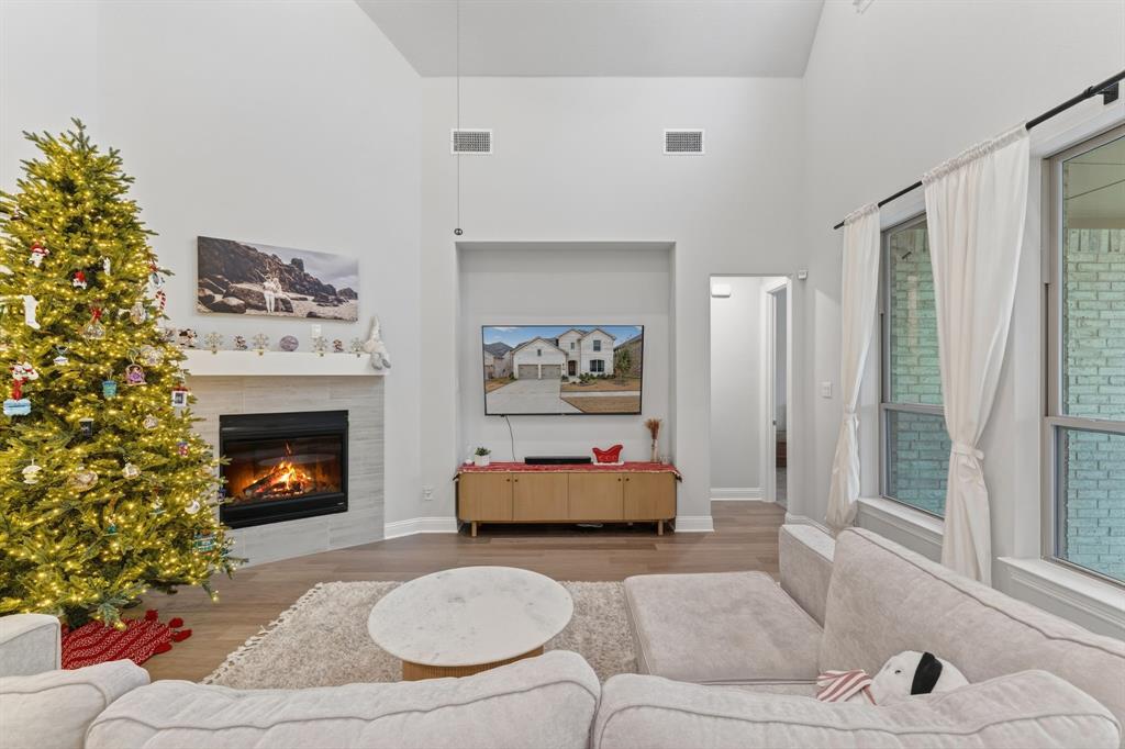 4150 Gambel Road Prosper, TX 75078 - Photo 13 of 39 Living area featuring a high ceiling, a tiled fireplace, and wood finished floors