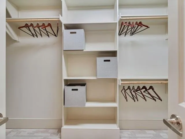 a walk in closet with wooden floor