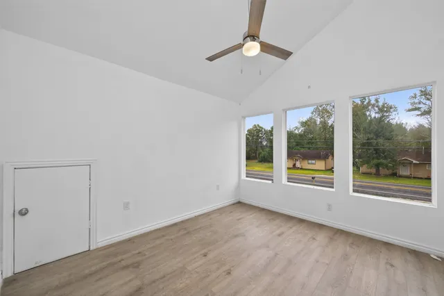 an empty room with wooden floor and windows
