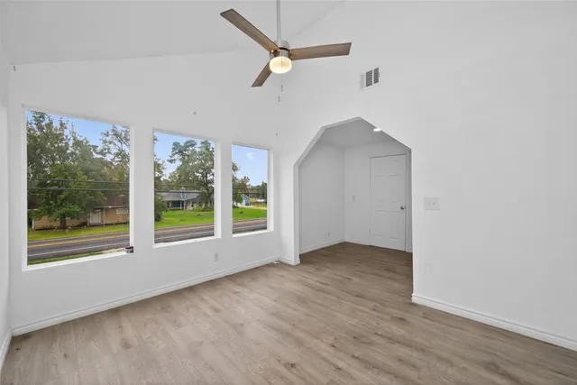 an empty room with wooden floor and windows