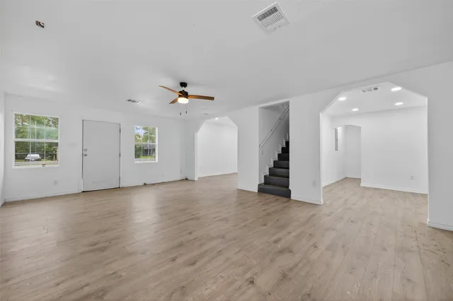 an empty room with wooden floor and windows