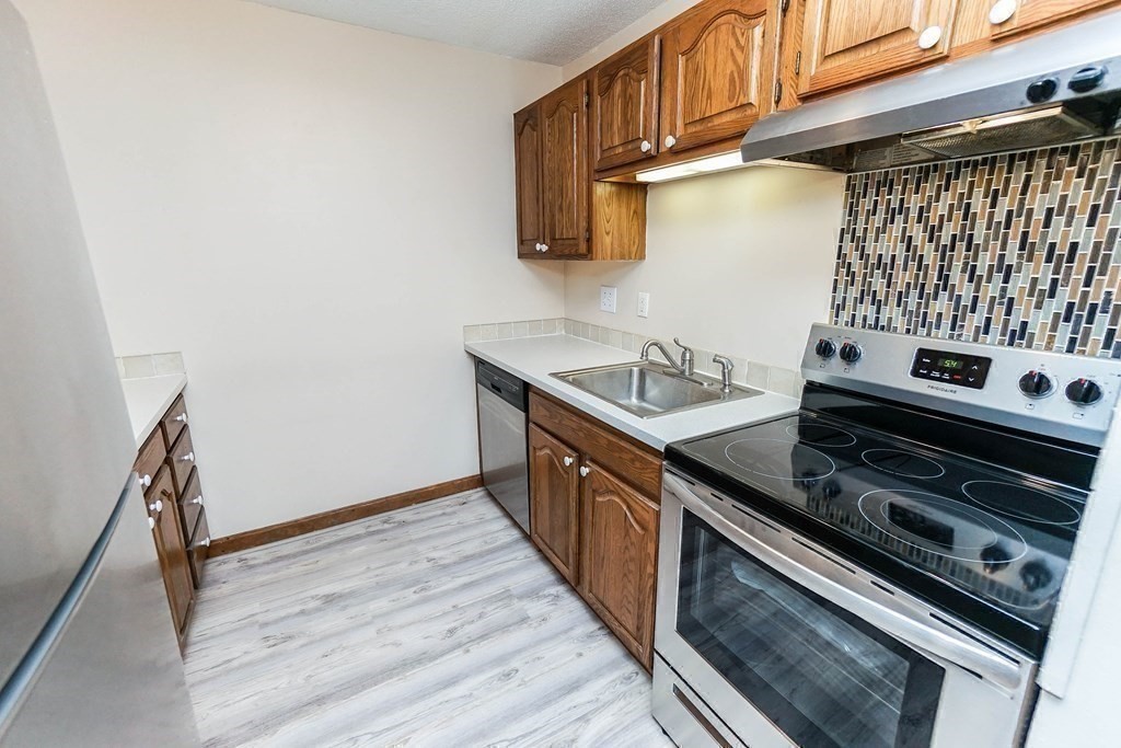 3 Summit Drive, Unit B2 Reading, MA 01867 - Photo 12 of 17 a kitchen with wooden cabinets and a stove top oven