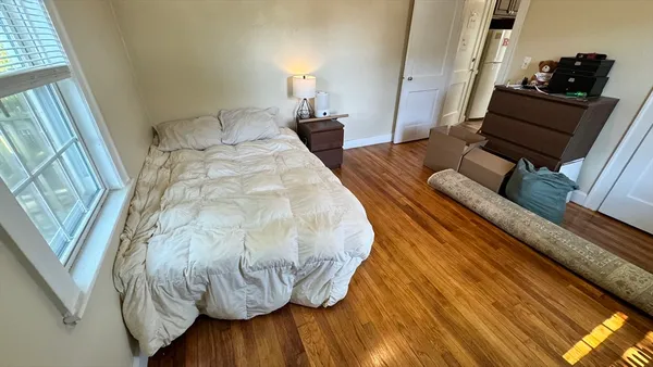 a bedroom with a bed and wooden floor