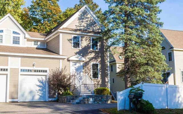 a view of a white house with a tree and wooden fence