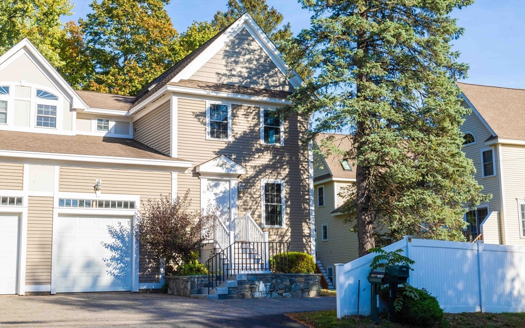 a view of a white house with a tree and wooden fence