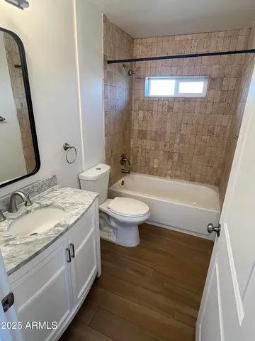 a bathroom with a granite countertop sink a toilet a mirror and shower