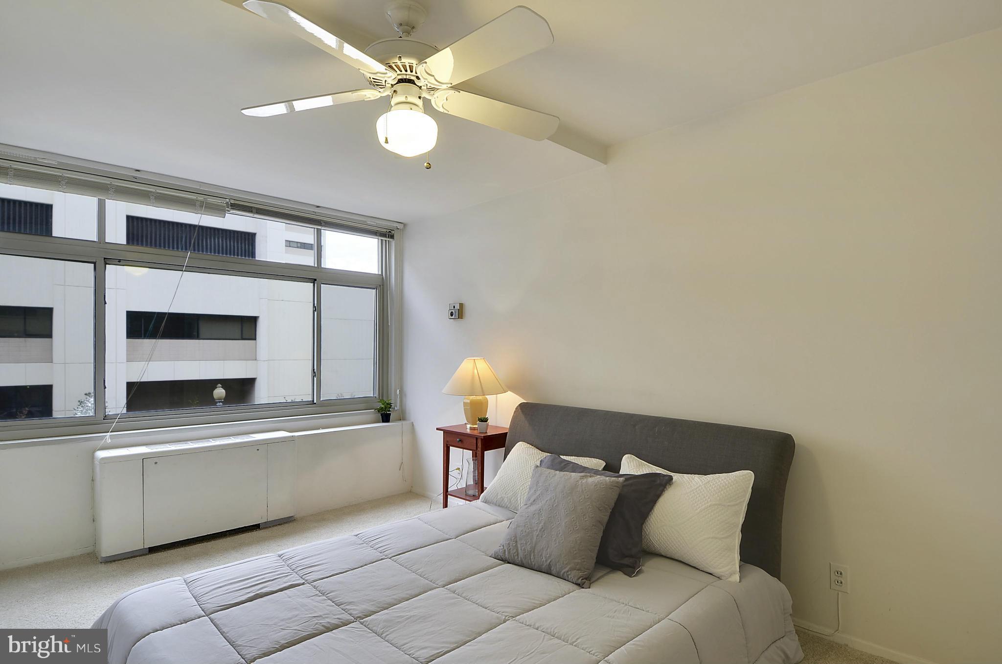 2401 H Street Northwest, Unit 309 Washington, DC 20037 - Photo 13 of 28 a spacious bedroom with a bed and a chandelier