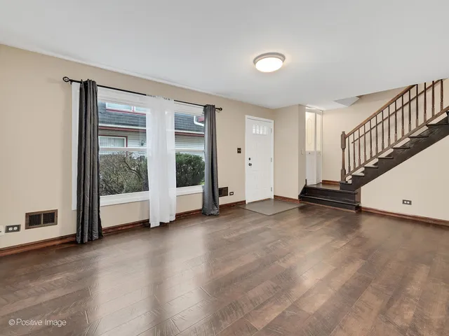 a view of an empty room with stairs and a window