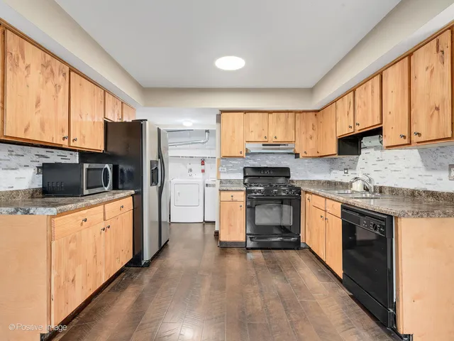 a kitchen with granite countertop a stove top oven a sink dishwasher a refrigerator and cabinets with wooden floor