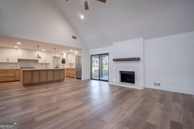 a kitchen with stainless steel appliances granite countertop a sink a stove a refrigerator a center island a wooden floor and white cabinets