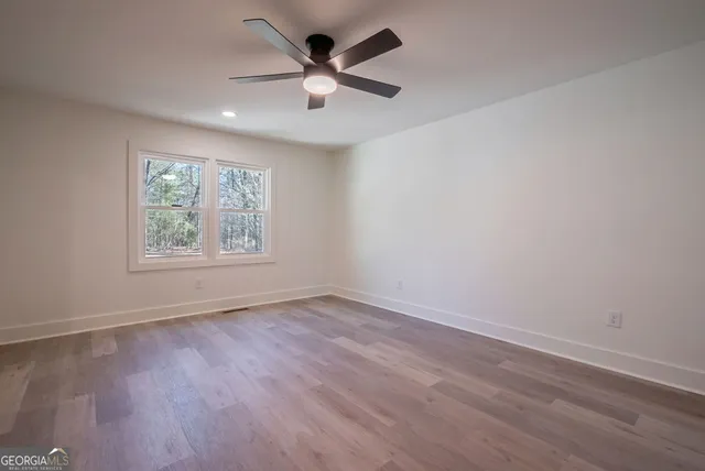 a view of an empty room with wooden floor and a window