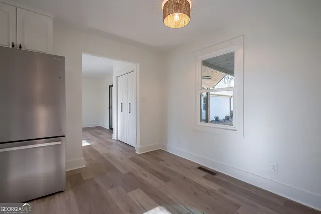 a view of an empty room with wooden floor and a window