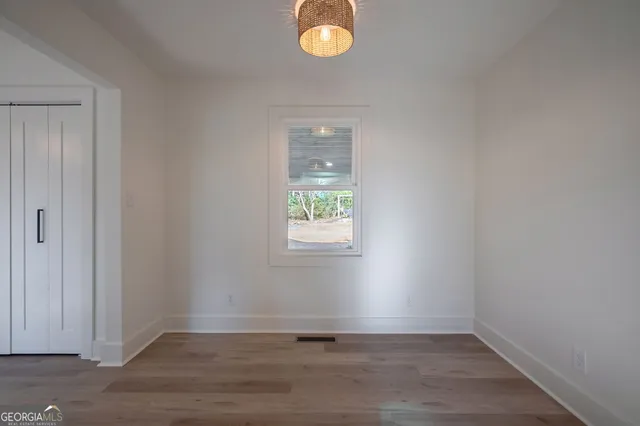 a view of empty room with wooden floor and fan
