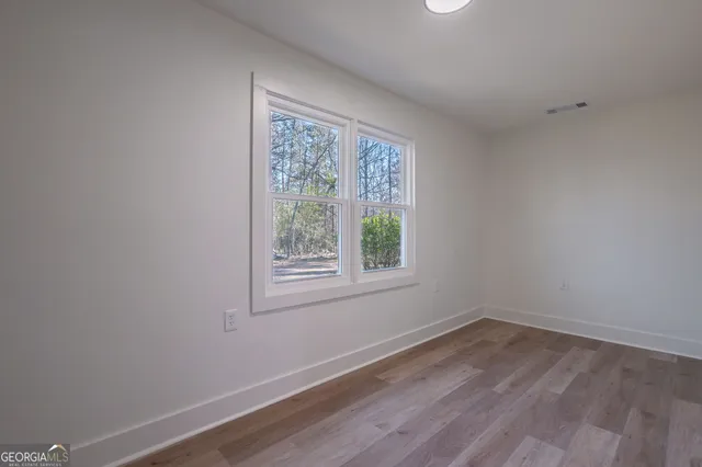 a view of an empty room with window and wooden floor