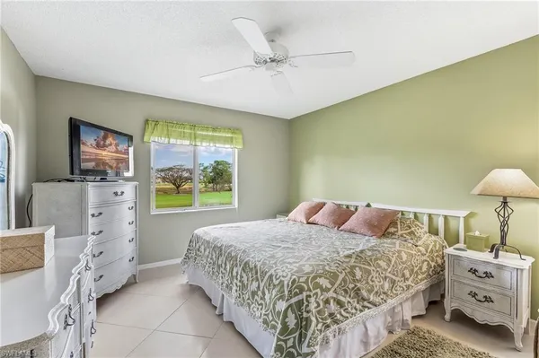 a bedroom with a bed and a flat tv screen on dresser