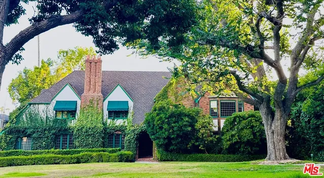 a front view of a house with a yard and potted plants